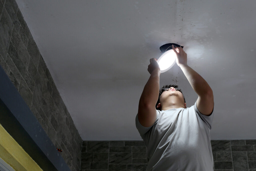 Electrician installing a recessed ceiling light for improved illumination